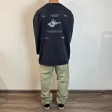 Buzo negro de corte oversize con estampado de concha marina y texto en la espalda.