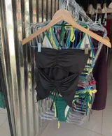 Top de bikini negro con escote bandeau, detalle de fruncido en el centro y abertura en el abdomen.