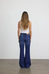 Jean de tiro alto, corte slim flare, en denim de sarga color azul medio con efecto levemente desgastado. Presenta cierre de botón y cremallera.