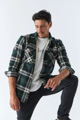 Sobrecamisa de algodón para hombre con interior de corderito, estampado a cuadros en tonos negro, blanco y azul. Tiene cierre de botones, bolsillos tipo cartera y logo en goma. El modelo usa talle M.