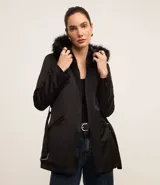 Campera parka negra con cuello alto, capucha con borde de piel sintética, cierre frontal con cremallera, bolsillos con cremallera y cinturón con hebilla.