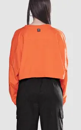 Remera corta naranja con mangas cortas abullonadas y ribete blanco en cuello, mangas y laterales.