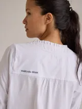 Remera color gris claro con cuello en V y volados de lino en el cuello.