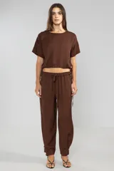 Pantalón de trabajo color marrón chocolate, de corte relajado, confeccionado en lino y tencel. Tiene bolsillos laterales, cintura elástica con cordón ajustable y detalle regulable en el tobillo.