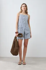 Chaleco con estampado a rayas verticales azules y blancas, con breteles finos y cierre frontal con botones. Presenta dos bolsillos frontales a la altura del pecho.