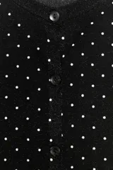 Chaqueta de punto fino negra con lunares blancos, cuello redondo, manga larga, terminaciones en rib y cierre frontal con botones.