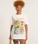 Remera de algodón color blanco, de corte alargado, con cuello redondo y manga corta. Presenta una estampa frontal de estilo tropical con palmeras, flores y texto 'Summer Tropical Beach'.