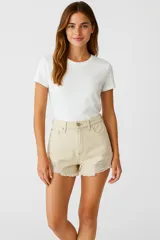 Short de jean color beige, de calce alto y con roturas y terminaciones desflecadas.