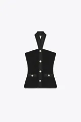 Top negro de tejido elástico con cuello halter y espalda descubierta. Presenta falsos bolsillos con botones metálicos en el delantero y cierre frontal con botones metálicos.