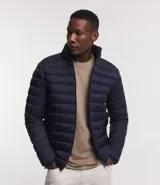 Campera puffer ultraligera color beige, con cuello alto, cierre por cremallera y bolsillos con cremallera. Incluye bolso de almacenamiento.
