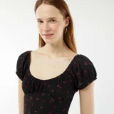 Vestido corto negro con estampado de flores rojas, escote cuadrado, mangas cortas abullonadas y cuerpo ajustado de tejido gofrado.