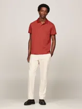 Chomba Tommy Hilfiger color ladrillo, de corte regular, con cuello clásico, cartera de tres botones y logo bordado en el pecho.
