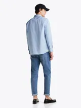 Camisa celeste de corte amplio confeccionada en sarga de puro algodón teñido en prenda, con cuello abotonado, bolsillo de parche en el pecho, puños redondeados con botón y logo de Tommy Hilfiger bordado en el bolsillo del pecho.