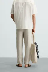 Pantalón de vestir blanco, confeccionado en lino, de corte recto, con bolsillos laterales y traseros. Se ajusta a la cintura con botón y cierre.