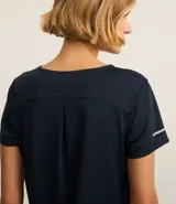 Remera deportiva blanca texturizada, con cuello redondo, manga corta, detalle reflectante y pliegue en la espalda.