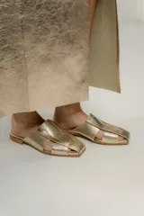 Zuecos negros con diseño de tiras entretejidas y suela plana color madera.
