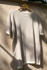 Remera roja de tejido artesanal en hilado 70% algodón y 30% acrílico, con cuello y mangas con ribete marrón. Corte holgado y aberturas laterales en el ruedo.