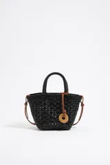 Bolso tipo tote tejido en color negro, con doble asa corta y correa de cuero sintético marrón. Incluye un dije circular con letras.