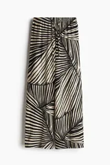 Pantalón de punto de corte holgado con piernas amplias, tiro alto, cintura elástica y cordón para ajustar. Estampado de hojas de palmera en blanco y negro.