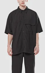 Camisa negra de manga corta con doble bolsillo ojal en delantero, realizada en tejido plano y silueta oversize.