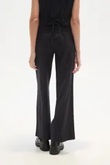 Pantalón de poliéster negro con rayas verticales blancas, de corte recto y tiro alto.