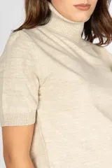 Sweater color beige de tejido de punto, con cuello alto y mangas cortas.