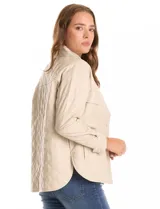 Chaqueta tipo camisa (shacket) de eco cuero color beige, con diseño acolchado en rombos, cuello camisero, botones frontales y dos bolsillos de parche en el pecho.