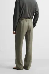 Pantalón negro regular fit confeccionado en tejido de lino. Cintura ajustable con cordón interior, bolsillos frontales y detalle de bolsillos traseros de vivo.