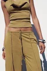 Pantalón ocre de algodón compacto, tiro medio, cintura elástica con cordón ajustable, pierna ancha y efecto lavado.