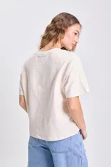 Camiseta de manga corta color crudo con apliques bordados en relieve con forma de flor en toda la prenda.