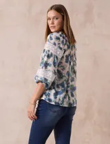 Blusa estampada con flores azules y verdes, cuello a la base con escote en V y volados. Manga larga con puño y apliques de puntilla.
