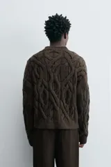Sweater marrón oscuro de punto con estructura de trenzas, cuello redondo, manga larga y corte regular fit.
