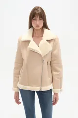 Campera tipo aviador de poliéster en color natural con forro de piel sintética a contraste. Presenta cuello de solapa, cierre frontal asimétrico con cremallera, bolsillos laterales con cierre y detalle de cremalleras en los puños.