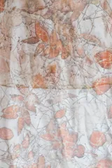 Pañuelo rectangular de seda color crema con estampado botánico en tonos naranja y marrón, realizado con hojas de eucalipto y casuarina.