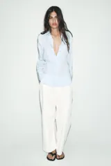 Camisa blanca de lyocell con cuello solapa, manga larga y bajo asimétrico. Cierre frontal con botones.