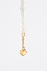 Collar doble con cadena dorada, una con perlas blancas irregulares y otra con una cuenta redonda con un corazón negro en el centro. Cierre con mosquetón y cadena de alargue con dije de corazón. Largo aproximado 52,5 cm.