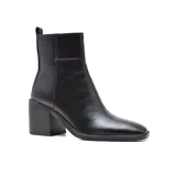 Botas de cuero negro con caña media, punta cuadrada y taco geométrico. Presentan un tirador trasero y elástico lateral para facilitar el calce.