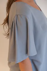 Blusa celeste de tela tipo jean, con escote en V y mangas cortas con volados.
