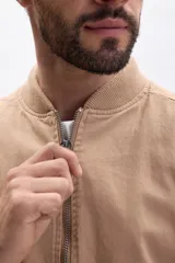 Campera estilo bomber de hombre, color tostado, con cierre frontal metálico, cuello y puños acanalados.