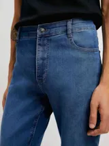 Pantalón de jean negro, corte ajustado (skinny), con tiro medio y cierre de botón y cremallera.