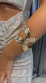 Brazalete dorado con diseño martillado y aberturas circulares.
