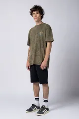 Remera de hombre color gris oscuro con efecto gastado (snow wash), corte semi-oversize y un pequeño estampado circular en el pecho que simula una obra de arte.