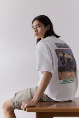 Remera blanca de algodón pesado con cuello redondo ribeteado, hombros caídos, bajo recto y estampado pequeño en el pecho. Corte oversized.