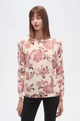 Sweater de tejido de punto, color crema, con estampado floral en tonos rosados y marrones. Presenta cuello redondo y mangas largas.