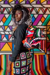Mochila Sprayground con estampado a cuadros en tonos grises y diseño de boca de tiburón con detalles multicolores.