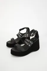 Sandalias negras con plataforma y taco de cuña, tiras de cuero con apliques de tachas plateadas y hebilla lateral.