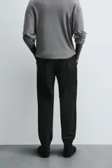 Pantalón jogger negro de corte slim fit, confeccionado en tejido de algodón con cintura elástica ajustable con cordón, bolsillos frontales y traseros de vivo, y bajo con puño elástico.