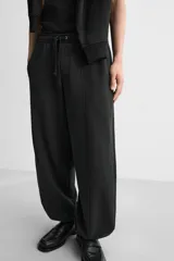 Pantalón de jogging negro, corte balloon fit, con cintura elástica ajustable con cordón, bolsillos laterales y trasero, costura frontal en las perneras y puños elásticos en los tobillos.