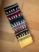 Clutch o neceser negro de neopreno con cierre de cremallera blanco y logo grande en blanco con tipografía serif.