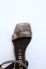 Sandalias de cuero charol negro con tira delgada sobre los dedos, pulsera con hebilla al tobillo y tacón cuadrado.